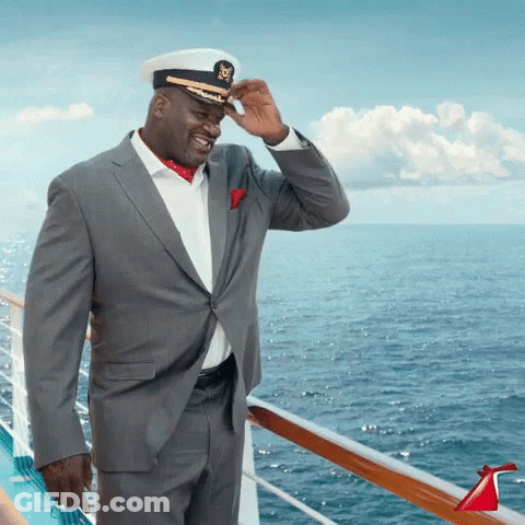 A Man In A Suit And Hat Is Standing On A Cruise Ship GIF