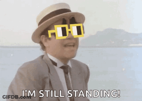 A Man In A Suit And Hat Is Wearing Sunglasses And Says I 'M Still Standing GIF