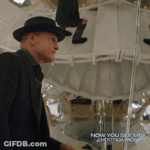 A Man In A Suit And Hat Stands In Front Of A Mirror With The Words Now You See Me GIF