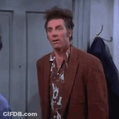 A Man In A Suit And Hawaiian Shirt Is Standing In A Room . GIF