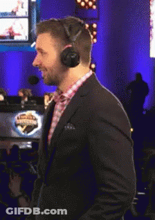 A Man In A Suit And Headphones Stands In Front Of A Sign That Says ' Champions ' On It GIF