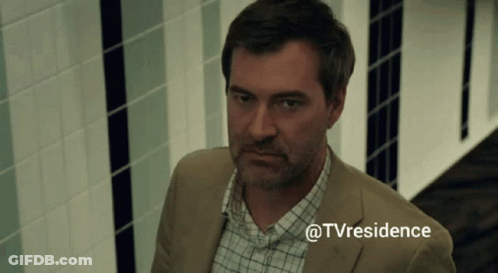A Man In A Suit And Plaid Shirt Is Standing In A Hallway With The Hashtag @Tvresidence GIF