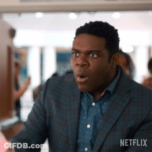 A Man In A Suit And Polka Dot Shirt Looks Surprised With His Mouth Open .. GIF