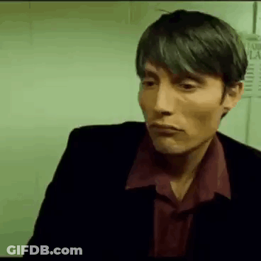 A Man In A Suit And Red Shirt Is Looking At The Camera . GIF