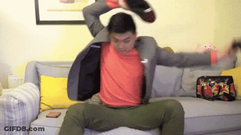 A Man In A Suit And Red Shirt Is Sitting On A Couch GIF