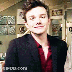 A Man In A Suit And Red Shirt Is Standing In A Living Room . GIF