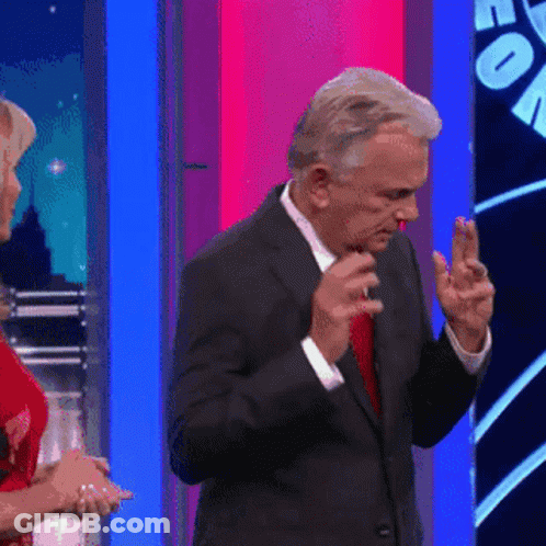 A Man In A Suit And Red Tie Is Dancing In Front Of A Woman In A Red Dress GIF