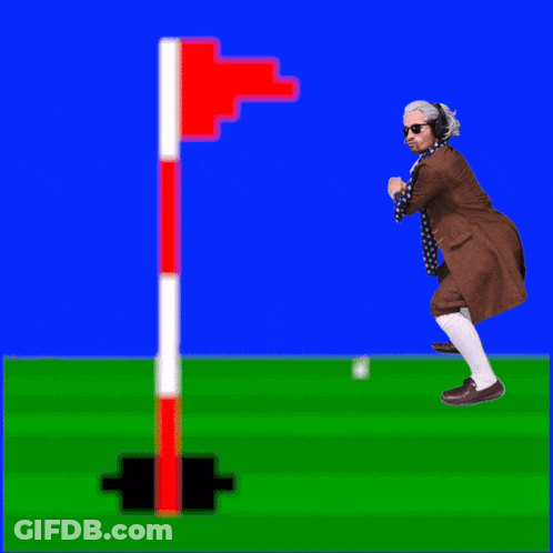 A Man In A Suit And Scarf Is Standing On A Golf Course GIF