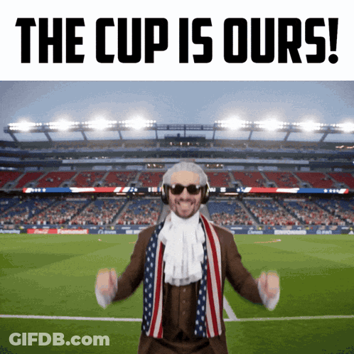 A Man In A Suit And Scarf Stands In Front Of A Soccer Stadium With The Words The Cup Is Ours GIF