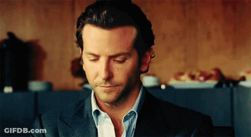 A Man In A Suit And Striped Shirt Is Looking Down With His Eyes Closed GIF