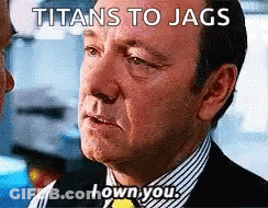 A Man In A Suit And Striped Shirt Is Talking To Another Man With The Caption Titans To Jags I Own You GIF