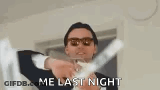 A Man In A Suit And Sunglasses Is Holding A Glass Of Champagne In His Hands . GIF