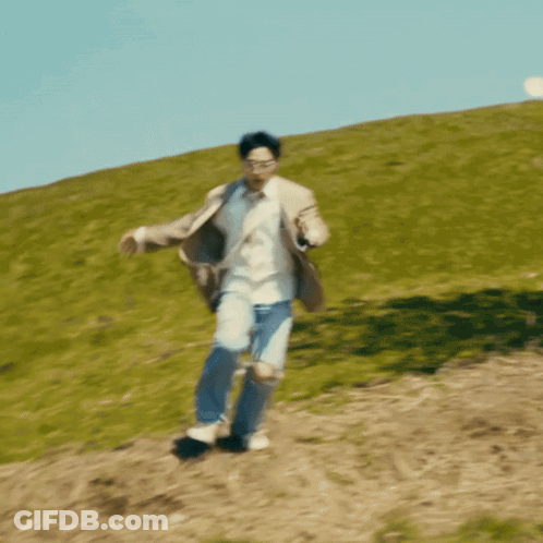 A Man In A Suit And Sunglasses Is Running Down A Hill GIF