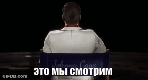 A Man In A Suit And Sunglasses Is Sitting In A Director 'S Chair With The Word Johnny Cage Written On It GIF