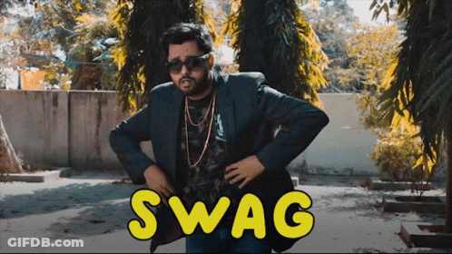 A Man In A Suit And Sunglasses Stands In Front Of A Sign That Says Swag On It GIF