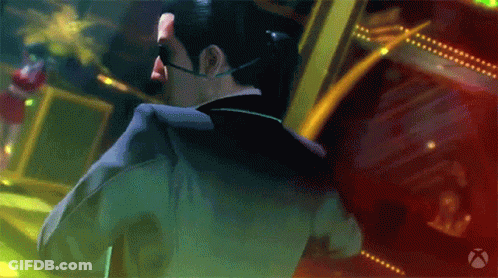 A Man In A Suit And Sunglasses Stands In Front Of A Xbox Logo GIF