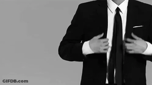 A Man In A Suit And Tie Adjusts His Tie GIF