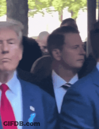 A Man In A Suit And Tie Has A Blue Ribbon On His Pocket GIF