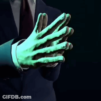 A Man In A Suit And Tie Has A Green Hand GIF