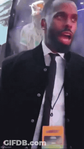 A Man In A Suit And Tie Has A Lanyard Around His Neck That Says ' Security ' GIF