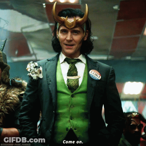 A Man In A Suit And Tie Has A Loki Bumper Sticker On His Vest GIF