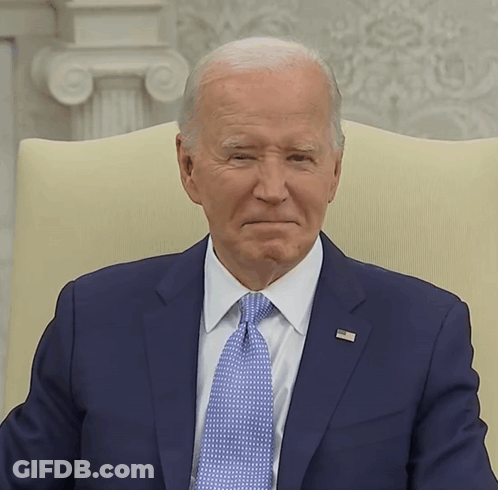 A Man In A Suit And Tie Has A Pin On His Jacket That Says ' United States Of America ' On It GIF