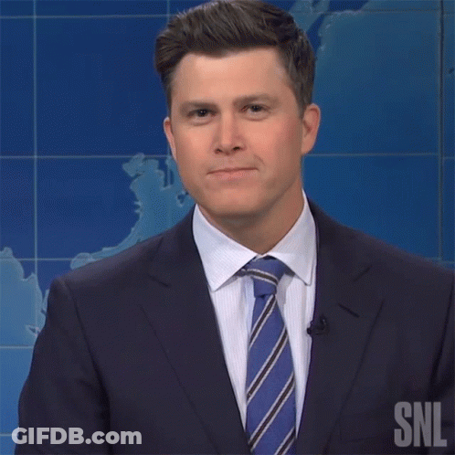 A Man In A Suit And Tie Has A Snl Logo On His Shirt GIF