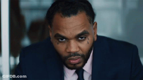 A Man In A Suit And Tie Has A Tattoo On His Face GIF