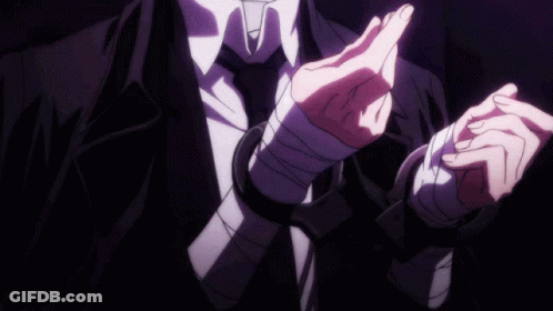A Man In A Suit And Tie Has His Hands Wrapped In Bandages And Handcuffs . GIF