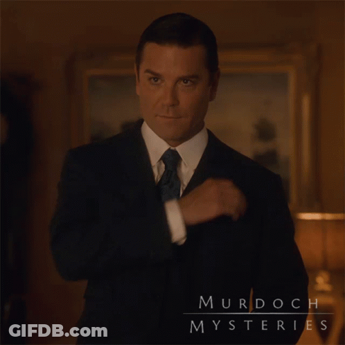 A Man In A Suit And Tie Has Murdoch Mysteries Written On His Chest GIF