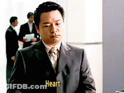 A Man In A Suit And Tie Has The Word Heart Written On His Jacket GIF