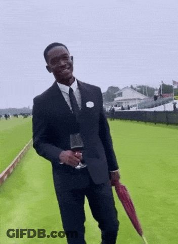 A Man In A Suit And Tie Holding A Glass Of Wine And An Umbrella GIF