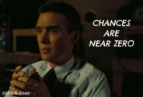 A Man In A Suit And Tie Holds A Cell Phone In Front Of A Screen That Says Chances Are Near Zero GIF