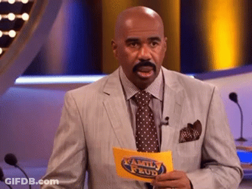 A Man In A Suit And Tie Holds A Family Feud Sign GIF