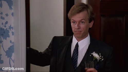 A Man In A Suit And Tie Holds A Glass In His Hand GIF