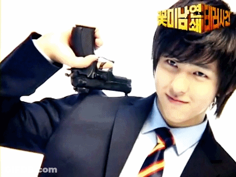 A Man In A Suit And Tie Holds A Gun In Front Of His Head GIF