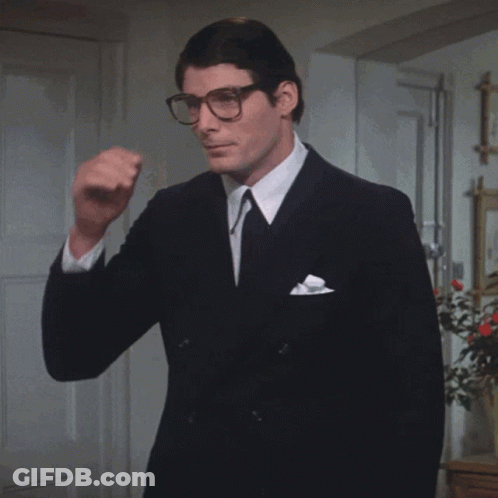 A Man In A Suit And Tie Holds A Pair Of Sunglasses GIF