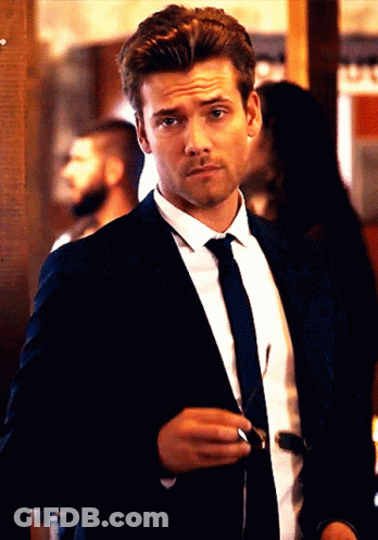 A Man In A Suit And Tie Holds A Pair Of Sunglasses In His Hand GIF