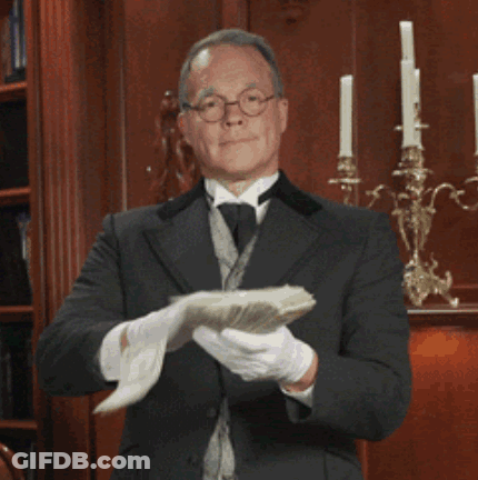 A Man In A Suit And Tie Holds A Piece Of Paper In His Hands GIF