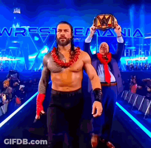 A Man In A Suit And Tie Holds A Wrestling Championship Belt GIF