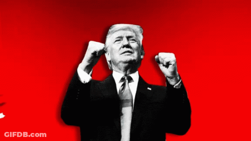 A Man In A Suit And Tie Holds His Fist In The Air GIF