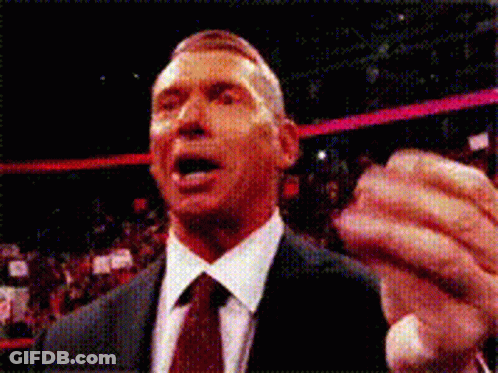 A Man In A Suit And Tie Holds His Fist Up GIF