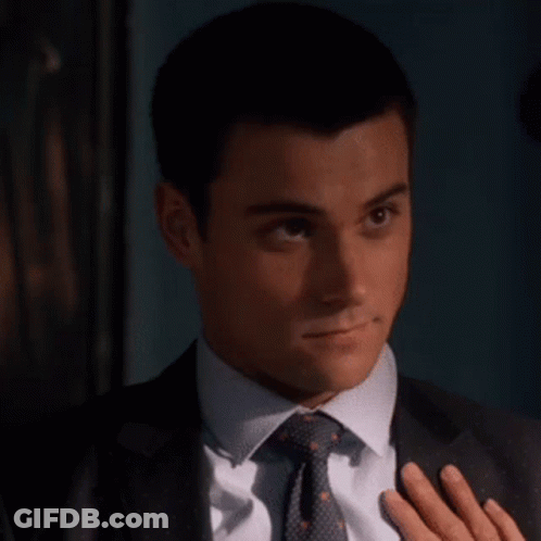 A Man In A Suit And Tie Holds His Hand To His Chest GIF