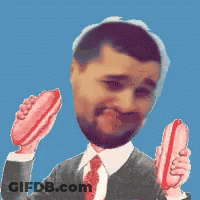 A Man In A Suit And Tie Holds Two Hot Dogs In His Hands GIF