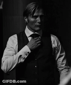 A Man In A Suit And Tie Is Adjusting His Jacket . GIF