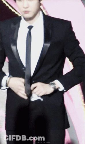 A Man In A Suit And Tie Is Adjusting His Suit Jacket GIF