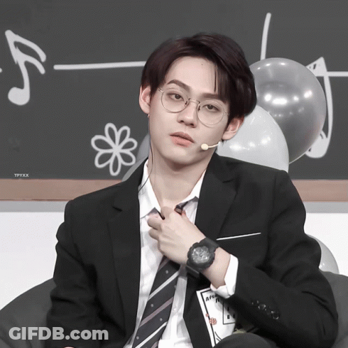 A Man In A Suit And Tie Is Adjusting His Tie While Wearing A Watch GIF