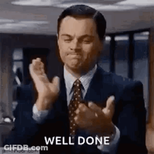 A Man In A Suit And Tie Is Applauding . GIF