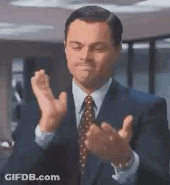 A Man In A Suit And Tie Is Applauding . GIF
