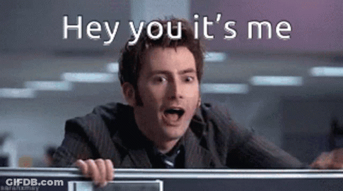 A Man In A Suit And Tie Is Behind A Desk And Says Hey You It 'S Me GIF